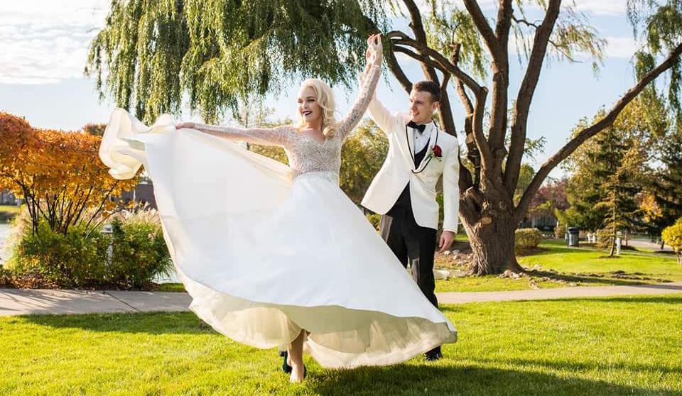 beautiful blonde bride in a white dress with her husband in tuxedo dancing outdoors One Salon wedding image